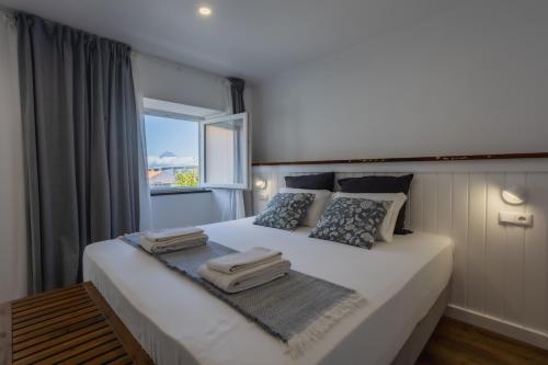 a bedroom with a large white bed with a window at São Jorge Holiday Homes in Velas