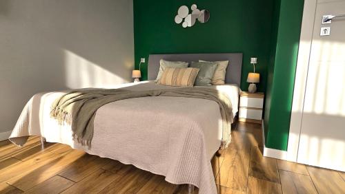 a bedroom with a bed with a green wall at Studio - Apartamenty Parkowe in Gniezno