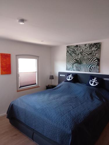a bedroom with a blue bed and a window at Heimathafen Hamelwörden in Wischhafen