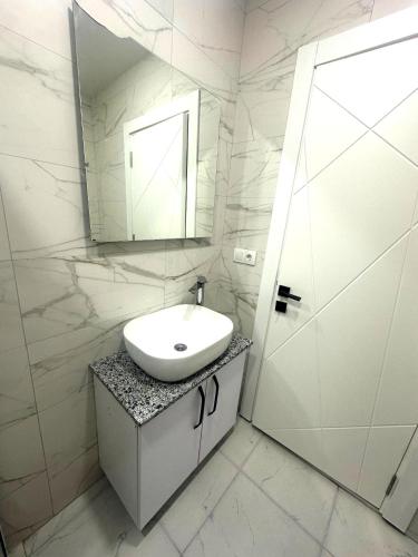 a white bathroom with a sink and a mirror at Ande Tower studio in Minda