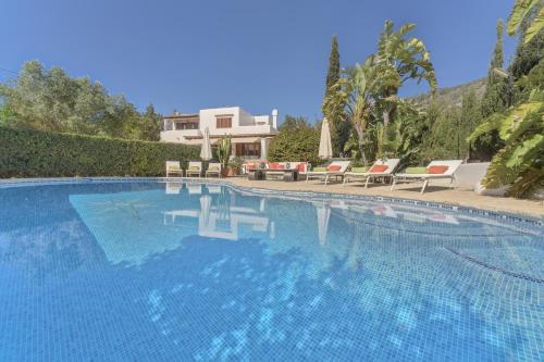 a swimming pool with chairs and a house in the background at Can Juanito in Playa d'en Bossa