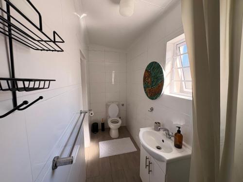 a white bathroom with a toilet and a sink at Cosy Coastal Hideaway in Hermanus