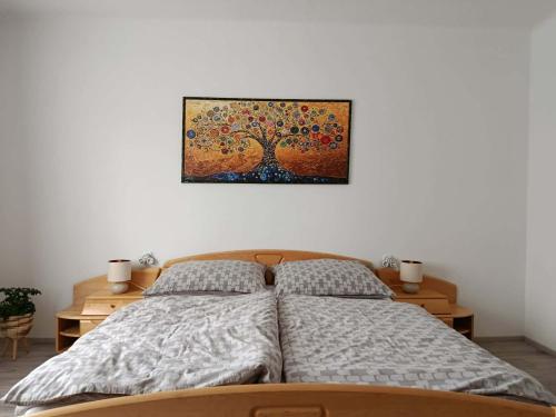 a bedroom with a bed with a tree picture on the wall at Apartman Silvia in Breitenau