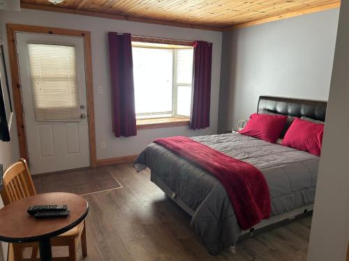 a bedroom with a bed with red pillows and a table at Noble Motel On Moore Lake in Norland