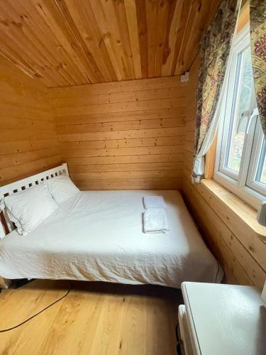 a bed in a wooden cabin with a window at Domek Zacisze całoroczny in Świętne
