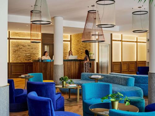 een lobby met blauwe stoelen en een bar bij Hotel Giacomo Morra Alba - Handwritten Collection in Alba
