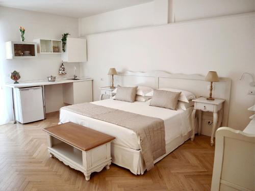 a white bedroom with a large bed and a table at Adagio Salentino in Porto Cesareo