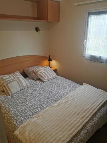 a bed with two pillows on it in a bedroom at Mobil-home cosy avec terrasse et jardin privatif in La Bernerie-en-Retz