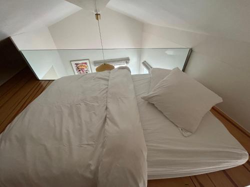 a white bed with two pillows in a room at La Garçonnière in Colombier