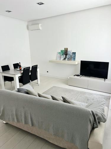 a white bedroom with a large bed and a table at AragonApartment in Santa Maria a Vico