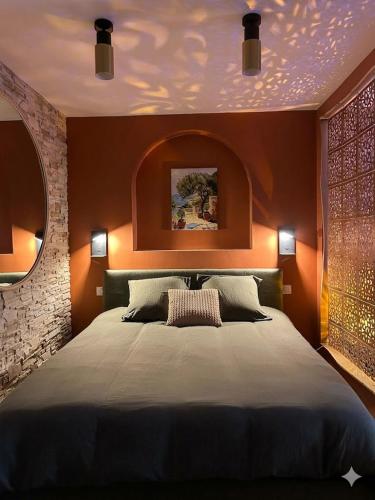 a bedroom with a large bed with orange lighting at La Casetta refuge méditerranéen et balnéo classé 3 étoiles in Wizernes