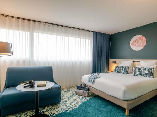 a hotel room with a bed and a chair at ibis Styles Bordeaux Lac Bruges in Bordeaux
