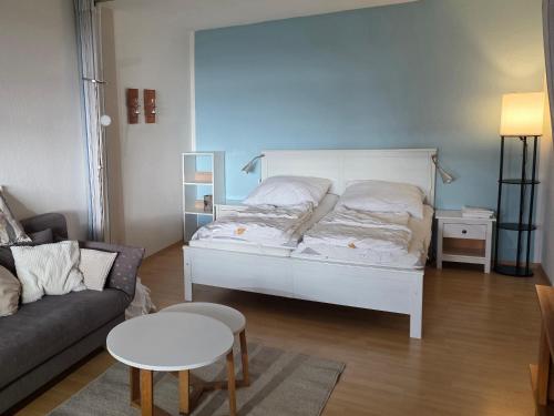 a bedroom with a white bed and a couch at FEWO-Luik H-1-6 in Heiligenhafen