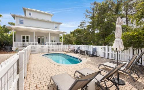 a white fence surrounds a pool with chairs and an umbrella at Ritz Clareon by Oversee 30A in Seacrest
