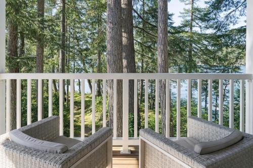 two chairs sitting on a porch with trees at Valhalla The Loft (Oceanfront Hot tub) in Salt Spring Island