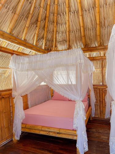a bed in a straw hut with a mosquito net at Playa Escondida Mayapo in Mayapo