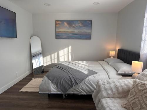 a white bedroom with a bed and a mirror at Cozy Home near Beaches, LAX, SoFi, Intuit Dome,405 in Hawthorne