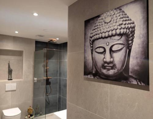 a bathroom with a painting of a buddha on the wall at De Tegel Suite in Anjum