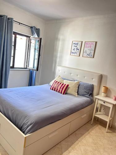 a bedroom with a bed with blue sheets and a window at Casa da Charrua in São Teotónio