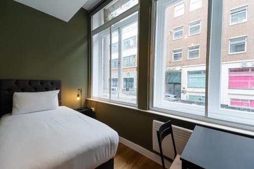 a bedroom with a bed and two windows at 8 Stanley Street Apart-Hotel in Liverpool