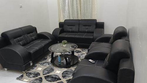 a living room with black leather couches and a table at GALSEN LODGe in Thiès
