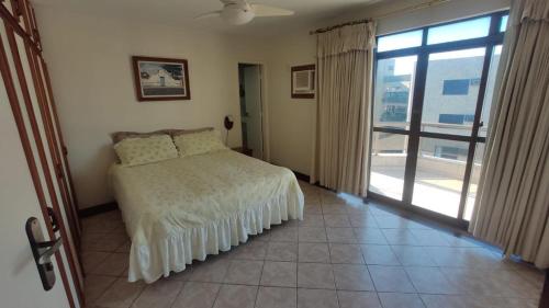 a bedroom with a bed and a large window at Varanda do forte in Cabo Frio