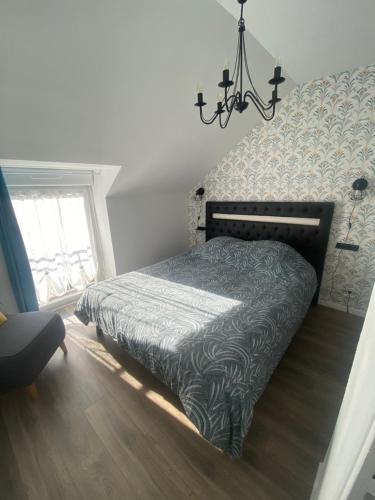 a bedroom with a bed and a chandelier at chez Sandrine in La Gacilly