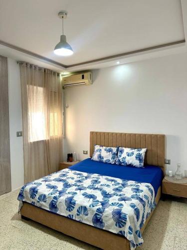 a bedroom with a bed with a blue and white comforter at Bord de Mer kelibia ezzahra in Ḩammām al Ghazzāz