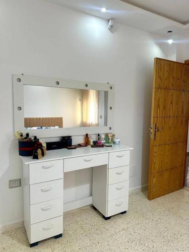 a white desk with a mirror and a wooden door at Bord de Mer kelibia ezzahra in Ḩammām al Ghazzāz