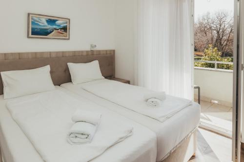 a bedroom with two beds with white sheets and a window at Lavanda Rooms & Apartment - Malinska in Malinska