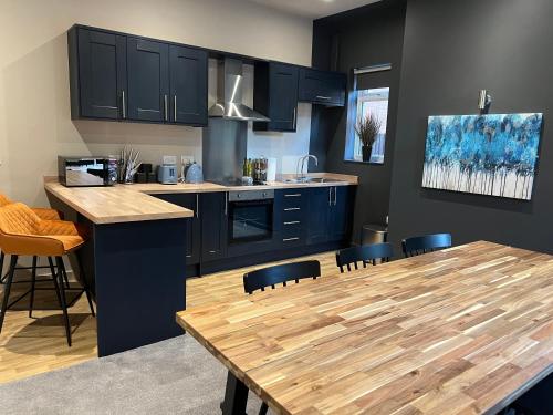 a kitchen with a wooden table and blue cabinets at Spacious 3 Bed Apartment Sleeps 8 Parking Garden in Loughborough in Loughborough