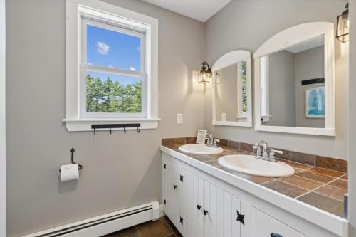 a bathroom with two sinks and a window at Wildflower Retreat in Kennebunk