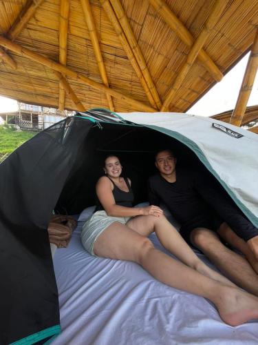 a man and woman laying on a bed in a tent at Conexión naturaleza in San Luis