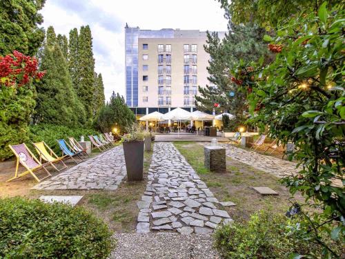 a stone path with chairs and a building in the background at Novotel Warszawa Airport in Warsaw