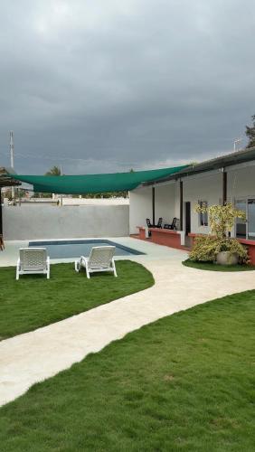 two white benches sitting in the grass near a pool at Monterrico VIP in La Candelaria