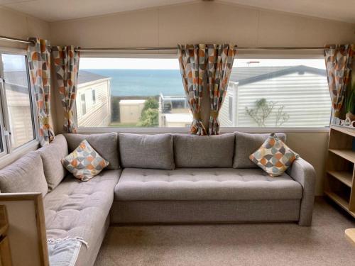 a living room with a couch and a large window at Torbay Holiday Home at The Waterside Holiday Park - With Deck and Sea View in Torquay