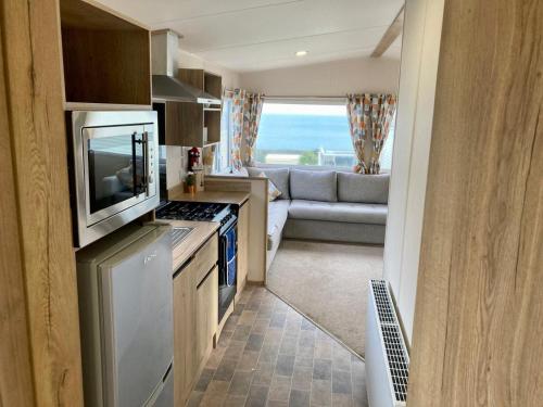 a kitchen with a television and a living room at Torbay Holiday Home at The Waterside Holiday Park - With Deck and Sea View in Torquay
