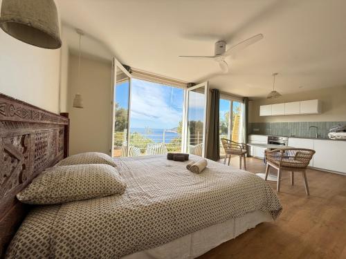 a bedroom with a bed and a kitchen with a view at La roche aux mouettes Ile du Levant in Île du Levant