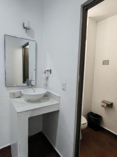 a white bathroom with a sink and a mirror at Aló Select Mazatlan in Mazatlán