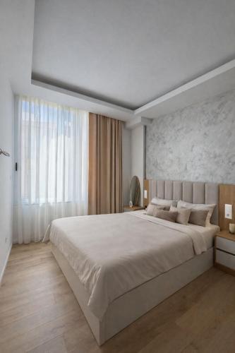 a white bedroom with a large bed and a large window at Paris and Eneas Studios in Vlorë