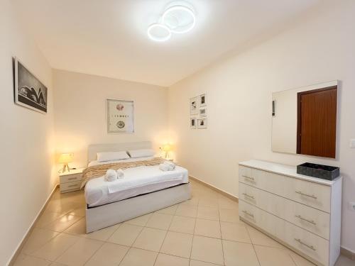 a white bedroom with a bed and a dresser at Bogdani Apartment in Golem