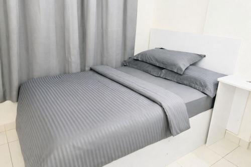 a bed in a white room with grey sheets at Angelic stay in Hulhumale