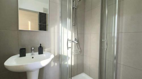 a white bathroom with a sink and a shower at Coralli Beachfront 1BDR Protaras in Paralimni