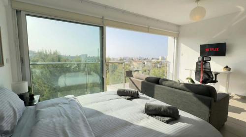 a bedroom with a bed and a large window at Coralli Beachfront 1BDR Protaras in Paralimni