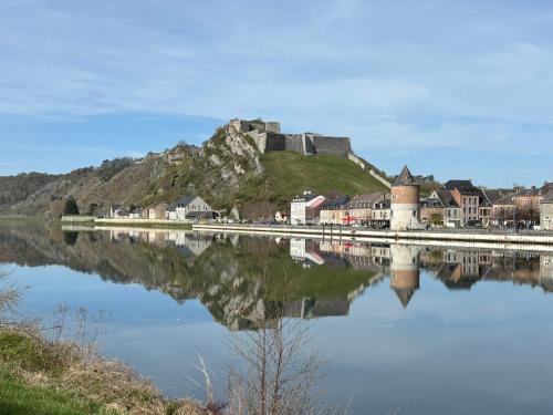 a castle on a hill next to a body of water at Studio Le Vale - Centre Ville de Givet in Givet