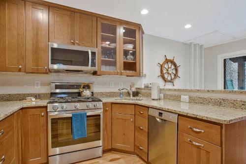 a kitchen with wooden cabinets and a stove top oven at Luxe Row Home Steps to USNA Gate 3 in Annapolis