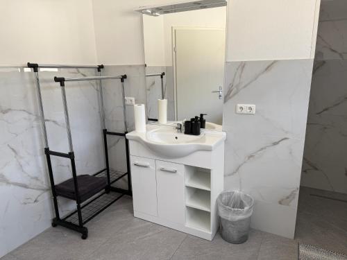 a white bathroom with a sink and a mirror at Ferienhaus von Werner in Schlatt