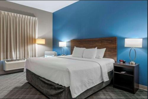 a large bed in a hotel room with a blue wall at Comfort Inn St Louis Airport in Bridgeton