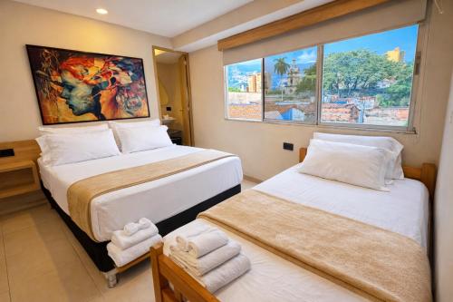 two beds in a room with two windows at HOTEL MEDELLIN CENTRAL in Medellín