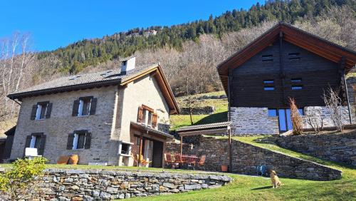 a stone house with a dog sitting in front of it at Casa Rongia in Faido